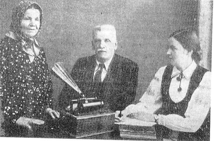 У час запісу беларускага фальклору. Стаіць: народная спявачка Уршуля Нэйжборт-Бяляўская, сядзяць: Сяргей Сахараў з дачкой Галінай (другая палова 1930-х гг.). Крыніца ілюстрацыі: Выбраныя творы / Вольга Сахарава, Сяргей Сахараў ; [укладанне, каментарыі М. Казлоўскага, С. Панізьніка ; прадмова М. Казлоўскага]. – Мінск, 2015. – С. 7 уклейкі паміж с. 304–305.