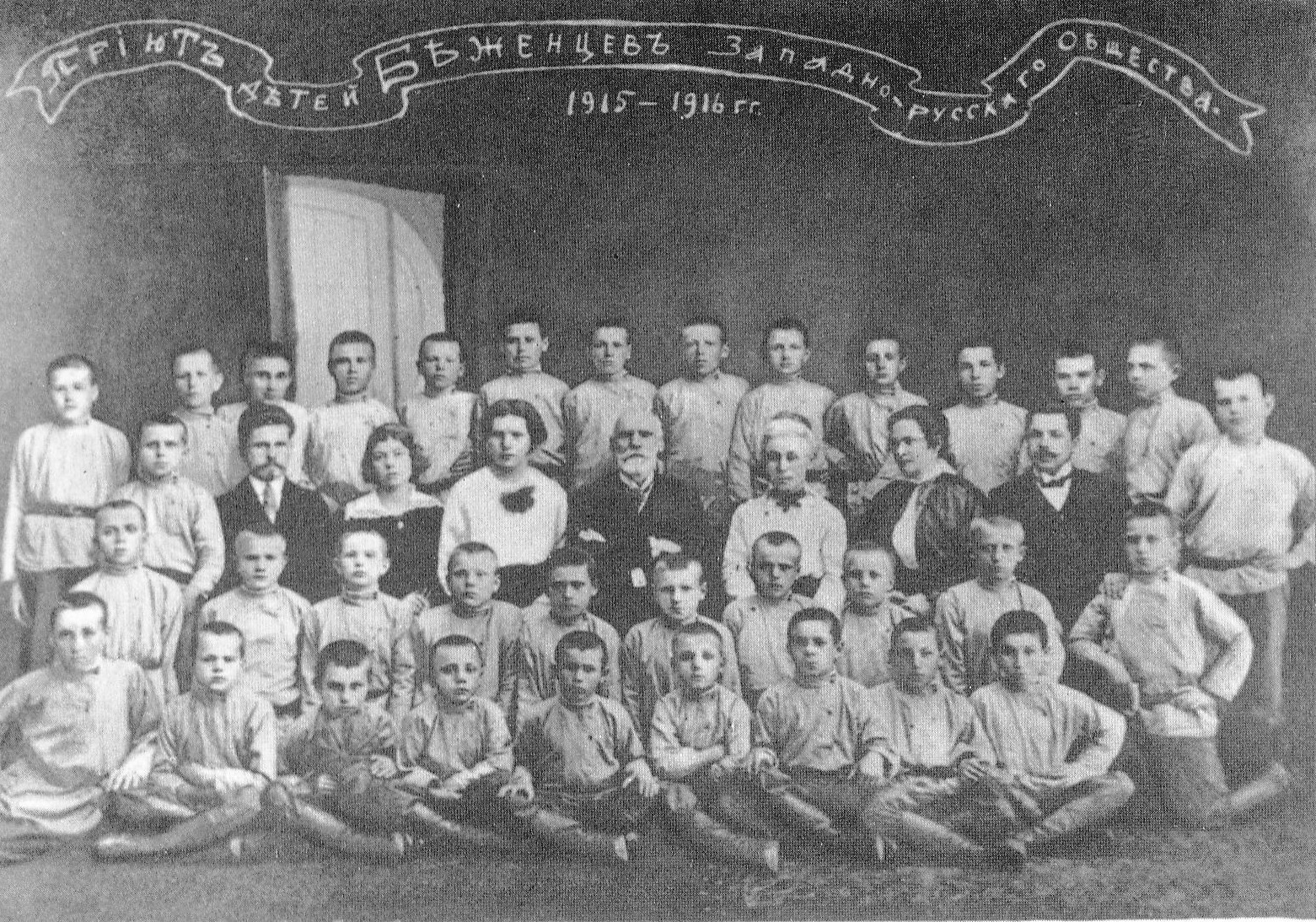 Рыгор Шырма з выхаванцамі прытулку для дзяцей бежанцаў-беларусаў у Яраслаўлі (сярод настаўнікаў першы злева, 1915–1916 гг.). Крыніца ілюстрацыі: Рыгор Шырма / аўтар-складальнік В. Дз. Ліцвінка. – Мінск, 1990. – С. 20.