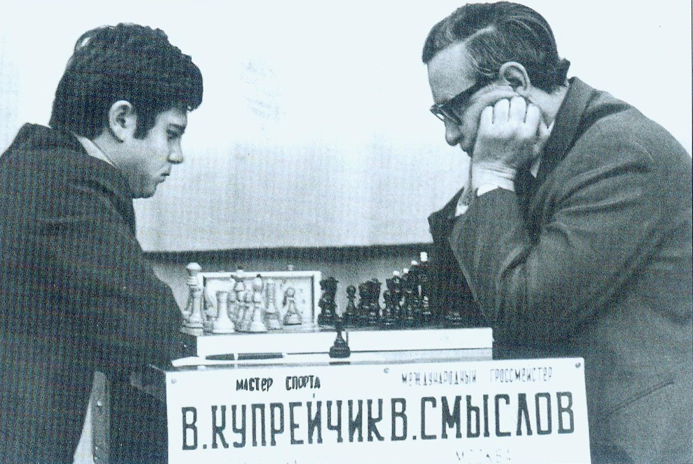 Во время матча между международным гроссмейстером В. Смысловым и мастером спорта В. Купрейчиком. Источник иллюстрации: Виктор Купрейчик: иду на вы : жизнь и творчество первого гроссмейстера Беларуси : [к 70-летию со дня рождения / составители: В. Л. Барский, А. В. Сорокина]. – Москва, 2019. – С. 9 вклейки между с 224–225. 