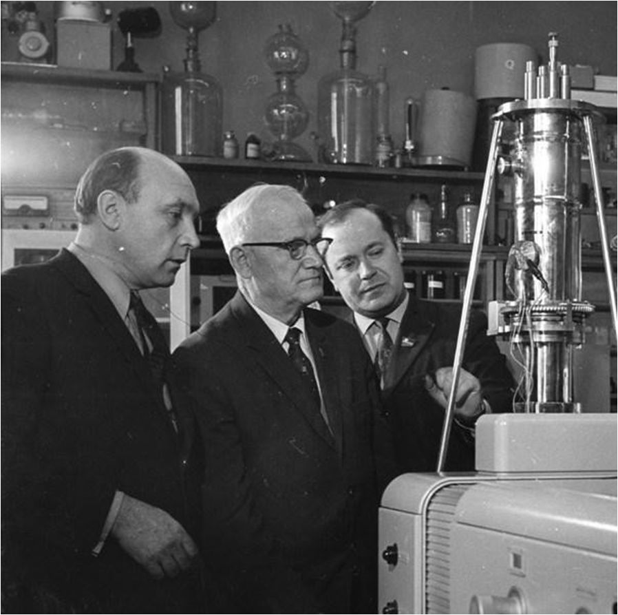 А.Н. Севченко в лаборатории кафедры лазерной физики и спектроскопии со своими первыми аспирантами, докторами физико-математических наук Л.В. Володько и Д.С. Умрейко (1960-е гг.). Источник иллюстрации: Интеллектуальная элита Беларуси. Основоположники белорусской науки и высшего образования (1919–1981) / [А. Д. Король и др. ; под общей редакцией А. Д. Короля]. – Минск, 2020. – С. 200. 