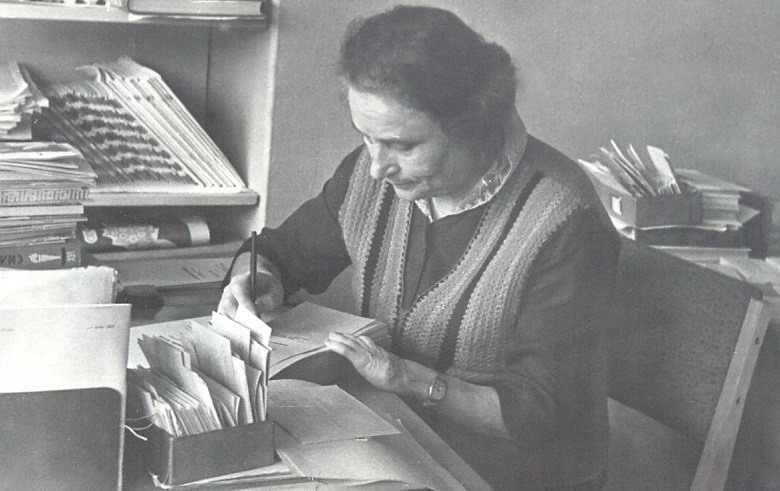 Ніна Варфаламееўна Каляда за рабочым сталом (пачатак 1960-х гг.). Крыніца ілюстрацыі: Калекцыя Нацыянальнай бібліятэкі Беларусі.
