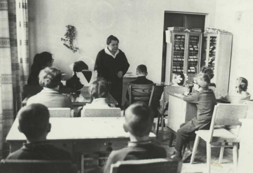 Зоя Уладзіміраўна Дзякава праводзіць заняткі з юнымі чытачамі Дзяржаўнай бібліятэкі БССР імя У.І. Леніна (1960-я гг.). Крыніца ілюстрацыі: https://www.nlb.by/by/infarmatsyynyya-resursy/elektronnyya-infarmatsyynyya-resursy/resursy-natsyyanalnay-bibliyateki-belarusi/virtualnyya-praekty-vysta-ki-i-kalektsyi/virtualnyya-praekty-bibliyateki/virtual/vyadomyya-imyeny/common/416049/#lg=1&slide=8
